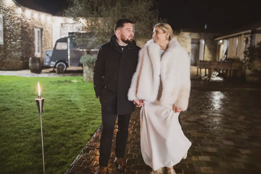 couple marchant à la lumière des flambeaux pendant un mariage d'hiver